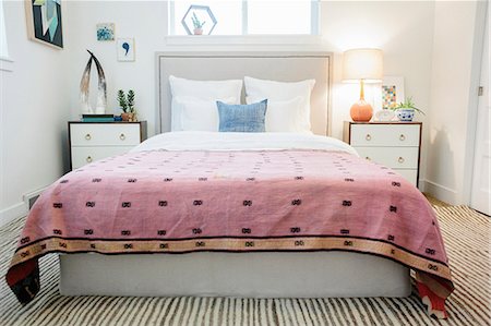 A bedroom in an apartment with a double bed and a retro look antique patterned patchworked bed cover. Fotografie stock - Premium Royalty-Free, Codice: 6118-08725851