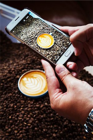 digital imaging - Specialist coffee shop. A person taking a picture with a smart phone of a cup of coffee on top of a heap of roasted coffee beans. Stock Photo - Premium Royalty-Free, Code: 6118-08725893