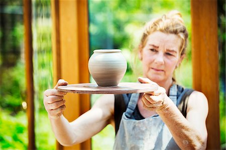 A potter examining a hand thrown pot, wet clay slip, rounded vase with tapering sides. Foto de stock - Sin royalties Premium, Código: 6118-08725947