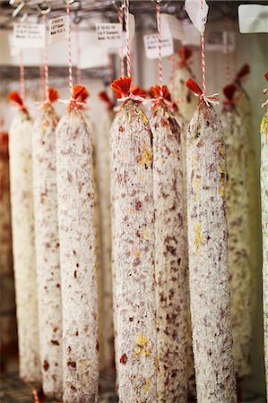 Close up of Chorizo sausages hanging from hooks in a charcuterie. Photographie de stock - Premium Libres de Droits, Code: 6118-08725977