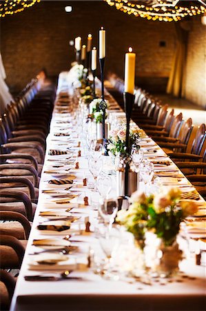 A wedding venue decorated for a party, with fairy lights and a long table set for dinner. Stock Photo - Premium Royalty-Free, Code: 6118-08726046