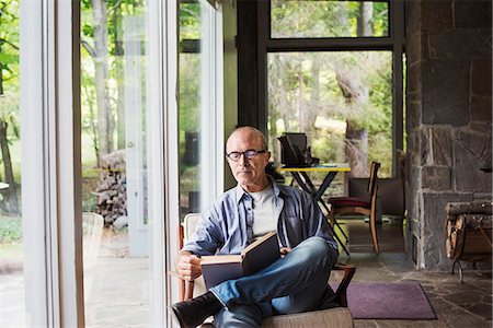 senior adults blue shirts - A man seated by a window reading a book. Stock Photo - Premium Royalty-Free, Code: 6118-08726128