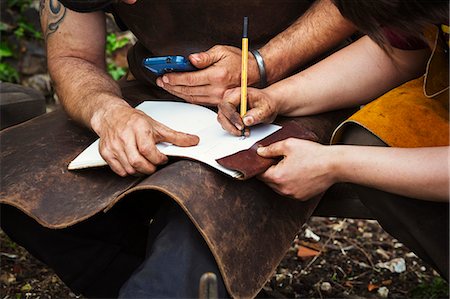 simsearch:6118-08729041,k - Man and woman, blacksmiths wearing aprons writing into a notebook sat in a garden. Stock Photo - Premium Royalty-Free, Code: 6118-08729050