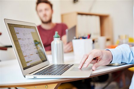 designer (graphic, male) - A man using a laptop and a man holding a digital tablet, working in an office. Stock Photo - Premium Royalty-Free, Code: 6118-08729091