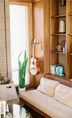 simsearch:6118-08394016,k - Interior view of a living room with sofa, coffee table, bookcase and an acoustic guitar hanging on a wall. Foto de stock - Sin royalties Premium, Código: 6118-08729167