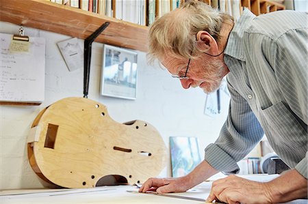 A violin maker at his drawing board drawing out the plans and outline for a new instrument. Photographie de stock - Premium Libres de Droits, Code: 6118-08729261