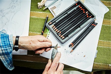 simsearch:622-02355053,k - A person using a sharp blade, a craft knife, to sharpen lead pencils. Sketches on paper. Stock Photo - Premium Royalty-Free, Code: 6118-08729281