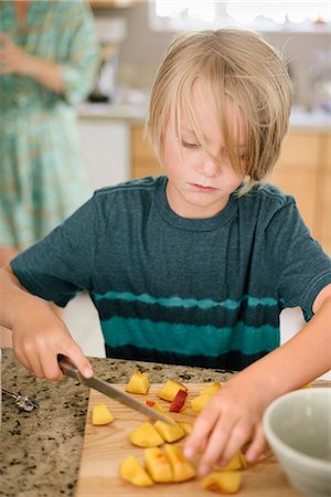 simsearch:6118-08729292,k - Family preparing breakfast in a kitchen, boy cutting fruit. Stockbilder - Premium RF Lizenzfrei, Bildnummer: 6118-08729297