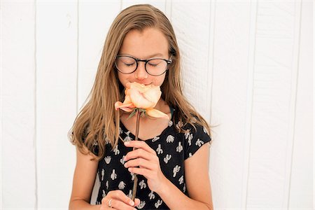 Girl with spectacles smelling a rose. Stock Photo - Premium Royalty-Free, Code: 6118-08729312
