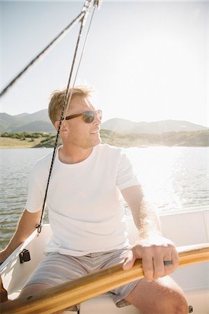 dirección (conducir) - Portrait of a blond man with sunglasses steering a sail boat. Foto de stock - Sin royalties Premium, Código: 6118-08729425