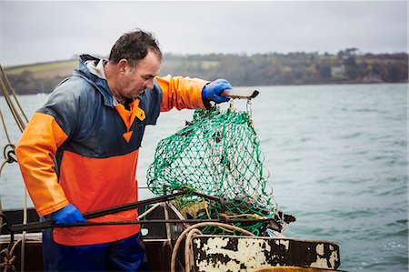 people and fishing boat and net - Traditional Sustainable Oyster Fishing. A fisherman opening a fishing creel on a boat deck. Stock Photo - Premium Royalty-Free, Code: 6118-08842096