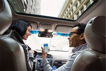 A young woman and young man in a car looking at a map on the display of a cellphone, seen from the back seat. Foto de stock - Sin royalties Premium, Código: 6118-08842154