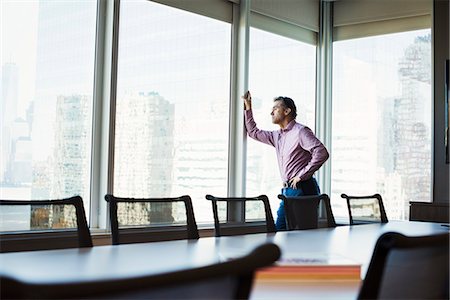 simsearch:614-08685284,k - A man in a meeting room looking out of a window at an urban landscape. Foto de stock - Sin royalties Premium, Código: 6118-08842163