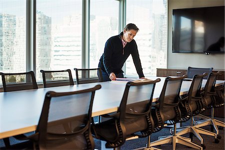 simsearch:614-08685284,k - A man standing at a table in a meeting room looking down at an open book. Foto de stock - Sin royalties Premium, Código: 6118-08842167