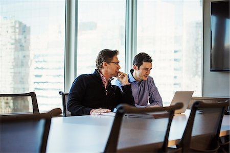 pictures of people seating on a table - Two men at a table in a meeting room looking at a laptop computer. Stock Photo - Premium Royalty-Free, Code: 6118-08842170