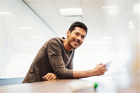 simsearch:6113-08105438,k - A young man sitting in a classroom leaning on a desk and smiling. Foto de stock - Sin royalties Premium, Código: 6118-08842200