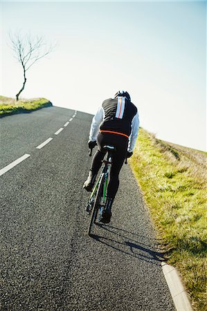 exercise men backside - A cyclist pedalling along a country road, rear view. Foto de stock - Sin royalties Premium, Código: 6118-08882934