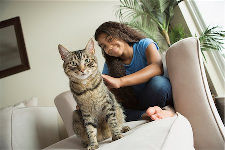 simsearch:6118-08725493,k - A girl sitting on a sofa with a pet cat. Stock Photo - Premium Royalty-Free, Code: 6118-08883050