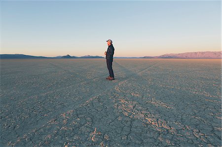 simsearch:6118-08827568,k - Man standing in vast desert playa at dawn, Black Rock Desert, Nevada Fotografie stock - Premium Royalty-Free, Codice: 6118-08827565