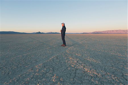 simsearch:6118-08860557,k - Man standing in vast desert playa at dawn, Black Rock Desert, Nevada Stock Photo - Premium Royalty-Free, Code: 6118-08827565