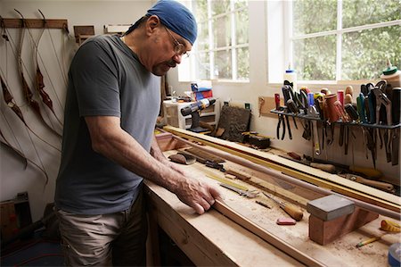 simsearch:6118-08729052,k - A bow maker working on a wooden bow in his workshop. Foto de stock - Sin royalties Premium, Código: 6118-08827521