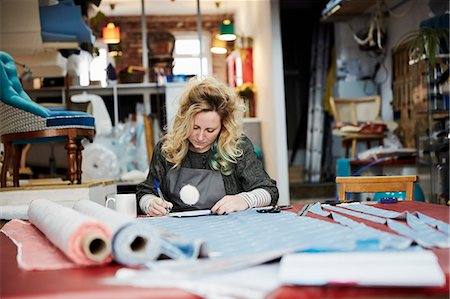 simsearch:845-05837814,k - A woman preparing, measuring and cutting upholstery fabric on a workbench. Foto de stock - Royalty Free Premium, Número: 6118-08827536