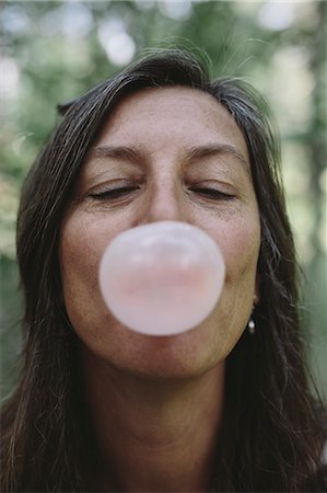 Portrait of middle aged woman blowing bubble gum bubble Stock Photo - Premium Royalty-Free, Code: 6118-08827605