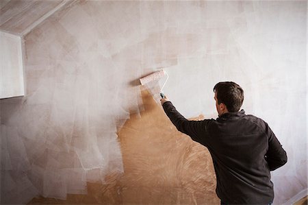 simsearch:614-01170958,k - A builder, a painter holding a paint roll, painting a wall with white paint. Foto de stock - Sin royalties Premium, Código: 6118-08947487