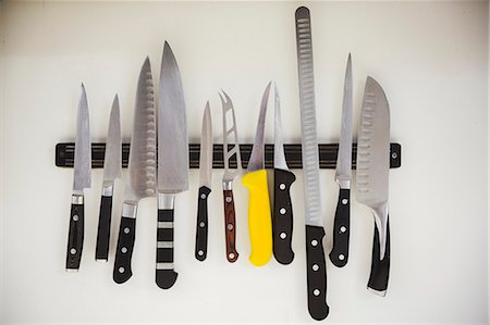 Close up of a selection of knives on a magnetic strip in a kitchen. Photographie de stock - Premium Libres de Droits, Code: 6118-08947550