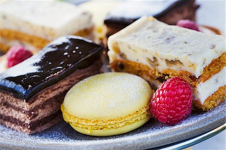 Close up of a selection of cakes, a cream slice and a macaroon and a raspberry on a plate, traditional afternoon tea. Stock Photo - Premium Royalty-Free, Code: 6118-08947555