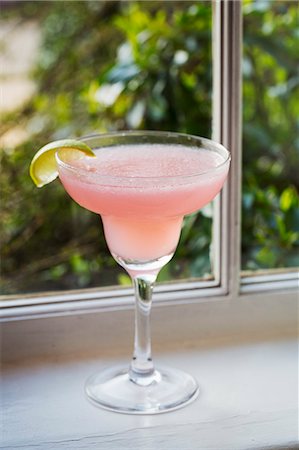 simsearch:6118-07440568,k - Close up of a pink drink in a cocktail glass decorated with a slice of lime Foto de stock - Sin royalties Premium, Código: 6118-08947563