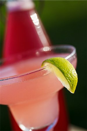 simsearch:6118-07440568,k - Close up of a pink drink in a cocktail glass decorated with a slice of lime Foto de stock - Sin royalties Premium, Código: 6118-08947567