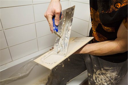 Close up of a builder, tiler spreading adhesive on the back a tile. Photographie de stock - Premium Libres de Droits, Code: 6118-08947506