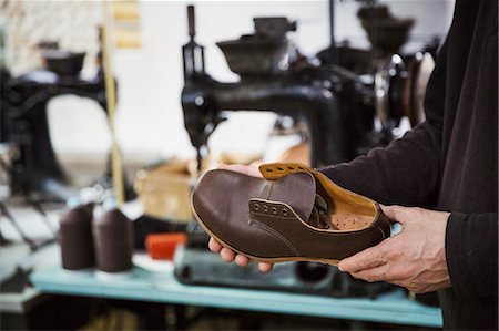 simsearch:6118-08947633,k - Man standing in a shoemaker's workshop, holding brown leather shoe. Photographie de stock - Premium Libres de Droits, Code: 6118-08947662