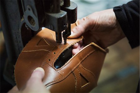 Close up of worker in a shoemaker's workshop, using a machine to punch holes into a leather shoe. Photographie de stock - Premium Libres de Droits, Code: 6118-08947667