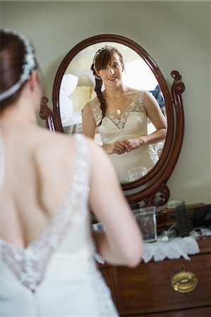 simsearch:6118-07521749,k - Smiling bride in her wedding dress looking at herself in a mirror. Photographie de stock - Premium Libres de Droits, Code: 6118-08947774