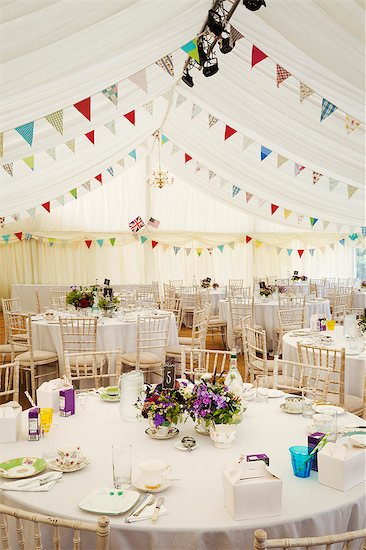 Interior view of a wedding marquee with set tables and decorated with bunting. Photographie de stock - Premium Libres de Droits, Le code de l’image : 6118-08947780