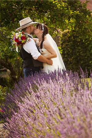 simsearch:6118-07521749,k - Newlyweds standing outdoors in a garden, hugging and kissing. Photographie de stock - Premium Libres de Droits, Code: 6118-08947785