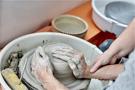 simsearch:6118-08660001,k - A person seated at a potter's wheel turntable, with hands on a wet clay lump, being taught to handle the clay. Stock Photo - Premium Royalty-Free, Code: 6118-08947841