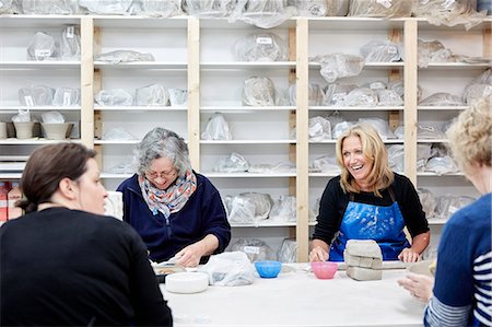 A group of four women chatting together and working on their pots in a pottery studio. Stock Photo - Premium Royalty-Free, Code: 6118-08947820