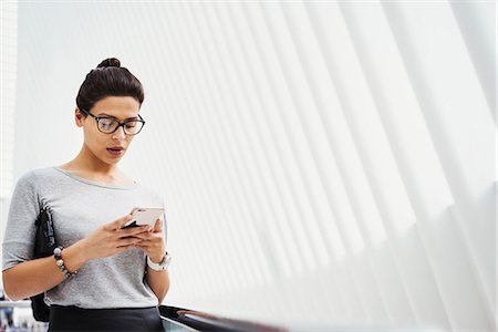 person, white background - A woman checking social media on her phone, in the airy atrium space of the World Trade Centre Oculus building. Stock Photo - Premium Royalty-Free, Code: 6118-08971293