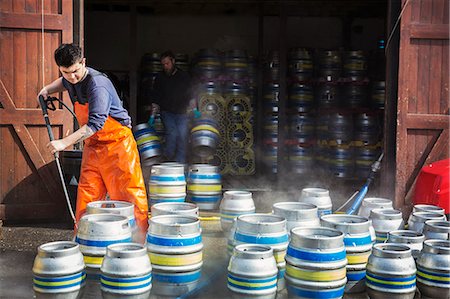 Man working in a brewery, cleaning metal beer kegs with a high pressure washer. Stock Photo - Premium Royalty-Free, Code: 6118-08971357