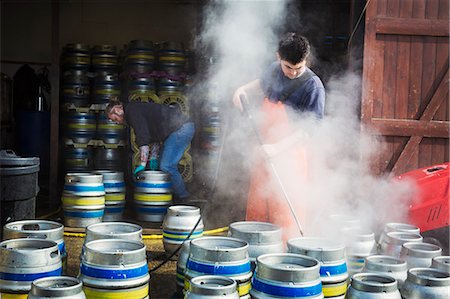 Man working in a brewery, cleaning metal beer kegs with a high pressure washer. Stock Photo - Premium Royalty-Free, Code: 6118-08971358