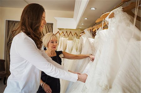 simsearch:6118-08971470,k - Two women, a young bride to be and a mature sales assistant looking through rails of wedding dresses. Photographie de stock - Premium Libres de Droits, Code: 6118-08971442