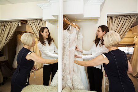 simsearch:6118-08971470,k - Two women, a client and retail advisor in a wedding dress shop, looking through the choice of gowns. Reflection in a large mirror. Photographie de stock - Premium Libres de Droits, Code: 6118-08971445