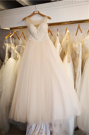 simsearch:6118-08971470,k - Rows of wedding dresses on display in a specialist wedding dress shop. A white dress on a hanger with a full net skirt. Photographie de stock - Premium Libres de Droits, Code: 6118-08971469