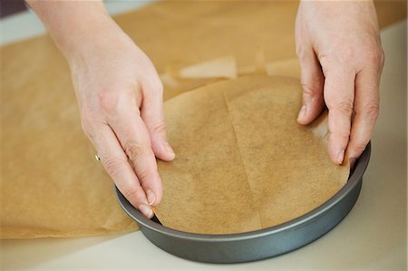 simsearch:6118-08971487,k - Close up high angle view of person lining the bottom of a round baking tin with baking paper. Stockbilder - Premium RF Lizenzfrei, Bildnummer: 6118-08971477