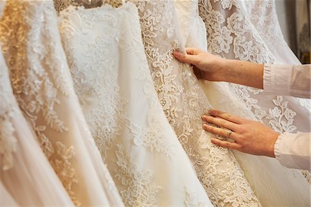 simsearch:6118-08971470,k - Rows of wedding dresses on display in a specialist wedding dress shop. Close up of full skirts, some with a lace overlay, in a variety of colour tones. . Photographie de stock - Premium Libres de Droits, Code: 6118-08971418
