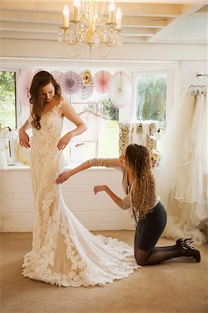 simsearch:6118-08971470,k - A dressmaker taking in a wedding dress, pinning and fitting it to the client, a young woman. A bride selecting her dress in a specialist shop. Photographie de stock - Premium Libres de Droits, Code: 6118-08971423