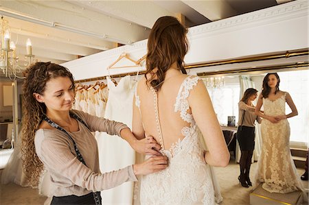 simsearch:6118-08971470,k - A dressmaker taking in a wedding dress, pinning and fitting it to the client, a young woman. A bride selecting her dress in a specialist shop. Photographie de stock - Premium Libres de Droits, Code: 6118-08971421